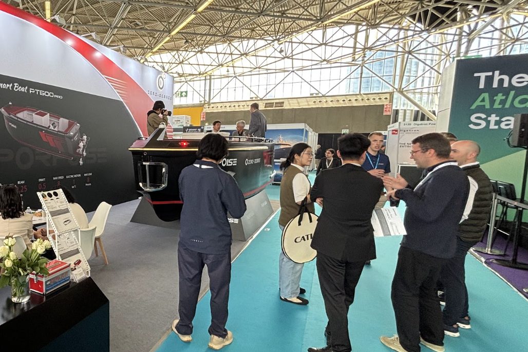 Visitors talking in an aisle of the Advanced Maritime Technology Expo exhibition floor at RAI Amsterdam, with vessel and propulsion displays behind them